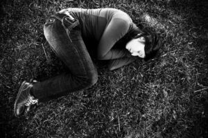 A greyscale photo of a woman lying on some grass