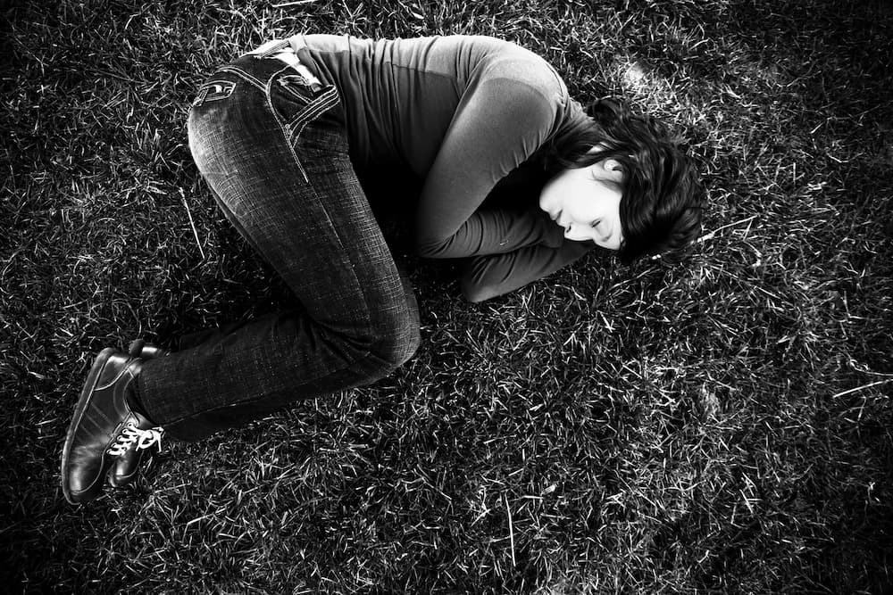 A greyscale photo of a woman lying on some grass