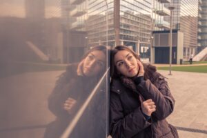 A woman looking pensive while standing next to a building